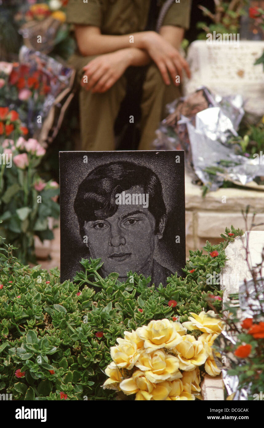 Una soldato israeliana si trova accanto alla tomba di un soldato caduto nel giorno commemorativo di Yom Hazikaron per i soldati caduti nel cimitero militare nazionale di Mount Herzl Gerusalemme Ovest Israele Foto Stock