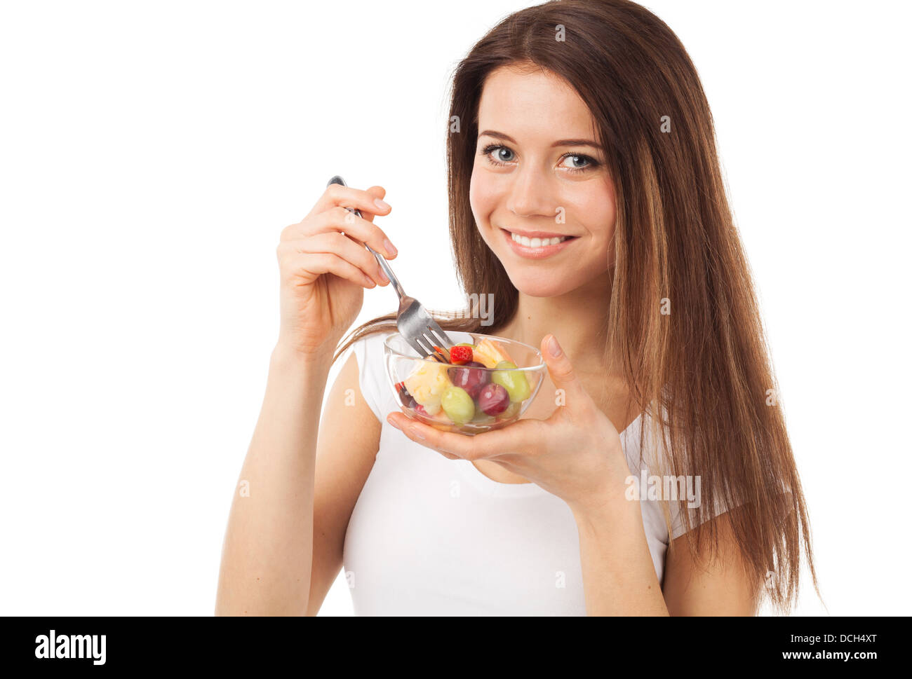 Bella giovane donna mangiare frutta e sorridente, isolato su bianco Foto Stock