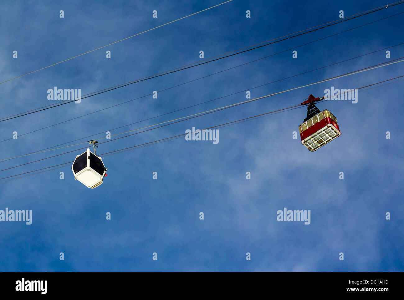 Antenna di vecchie linee tranviarie e una nuova funivia nelle montagne sullo sfondo del cielo nuvoloso in una giornata di sole. Foto Stock