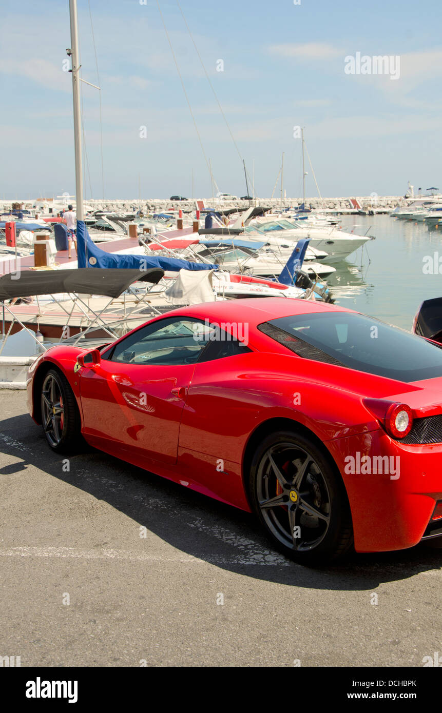 Ferrari 458 Italia parcheggiato di fronte a una fila di yacht in Puerto Banus a Marbella, Spagna. Foto Stock