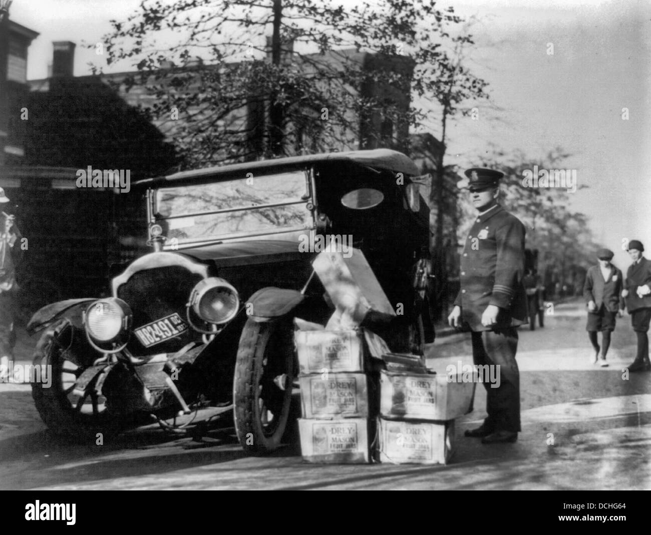 Poliziotto in piedi accanto ad auto disastrate e casi di moonshine, durante il divieto USA circa 1922 Foto Stock