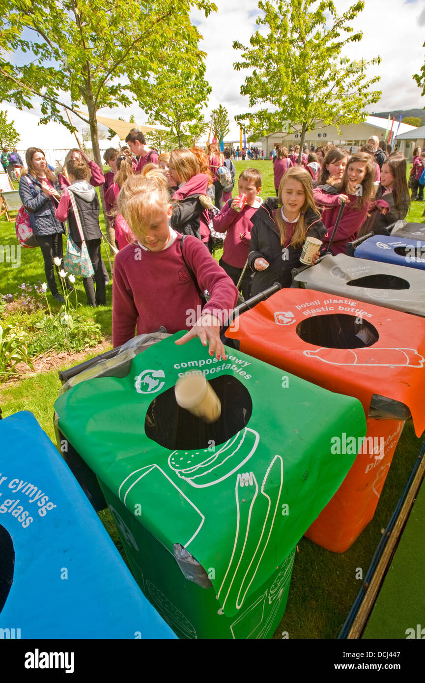 La scuola dei bambini presso il festival di fieno mettendo dei contenitori per i rifiuti in un contenitore per il riciclaggio. Foto Stock