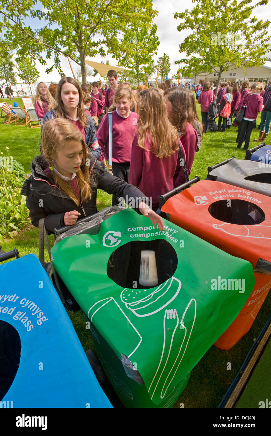 La scuola dei bambini presso il festival di fieno mettendo dei contenitori per i rifiuti in un contenitore per il riciclaggio. Foto Stock