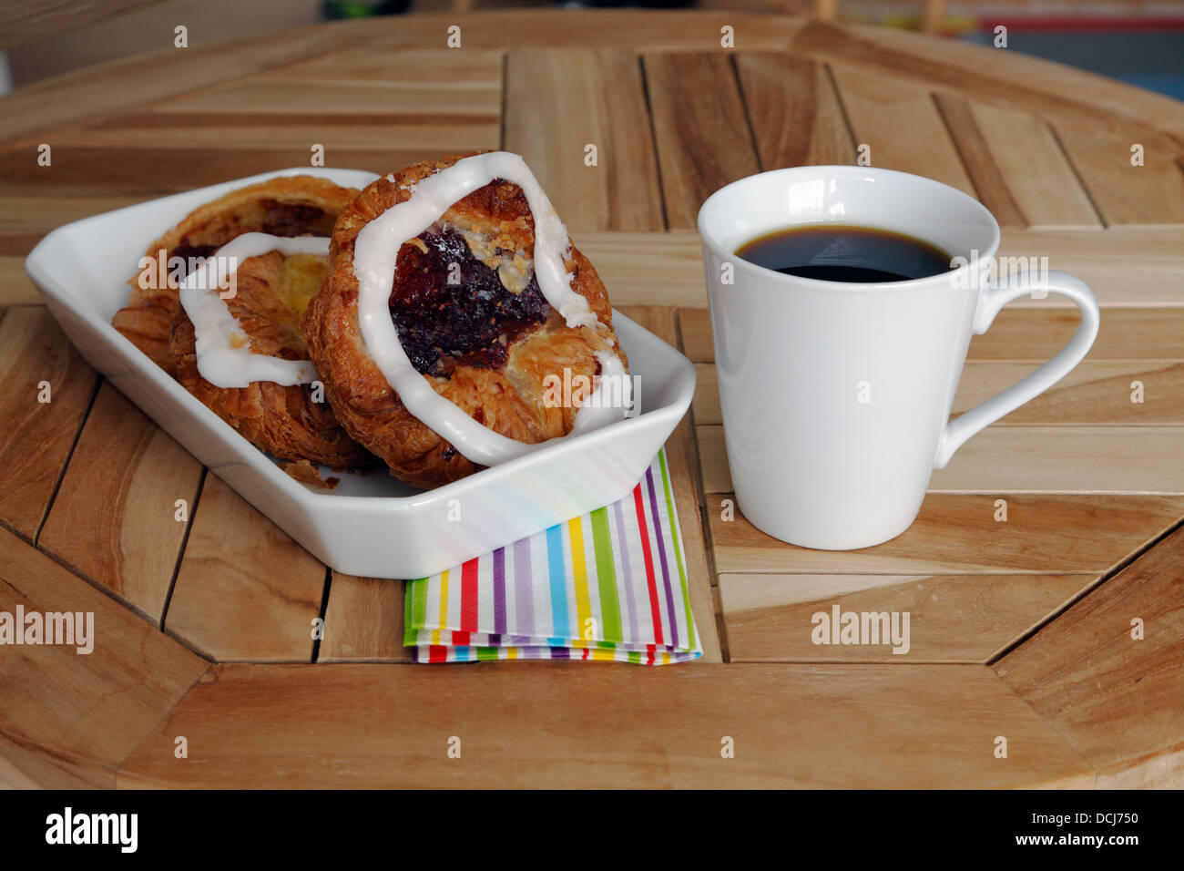 Originale pasticceria danese di laminato di lievito di pasta lievitata - friabile e delicato crosta e una tazza di caffè su una tabella di caffè. Foto Stock