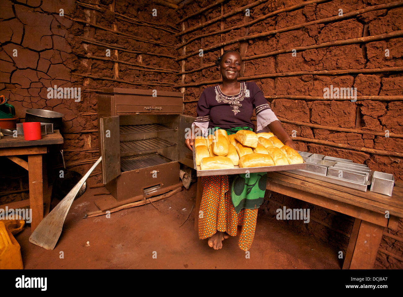 Donna della Tanzania con pane appena sfornato pani e efficienza energetica del carbone forno, Regione Miono, Tanzania Foto Stock