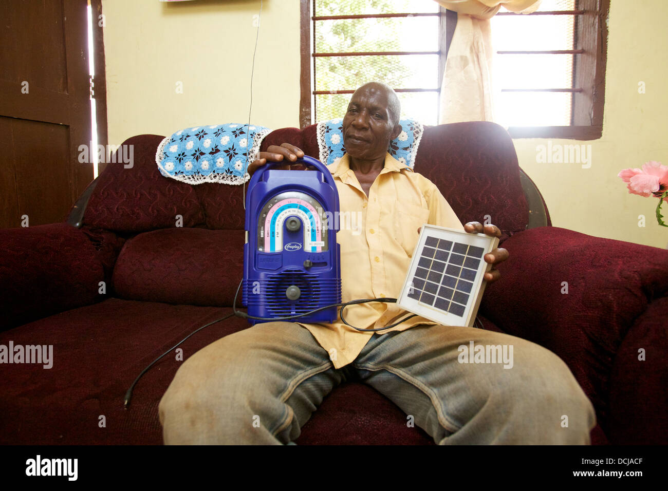 L'uomo della Tanzania a home azienda wind-up e radio portatile pannello solare, Regione Miono, Tanzania. Foto Stock