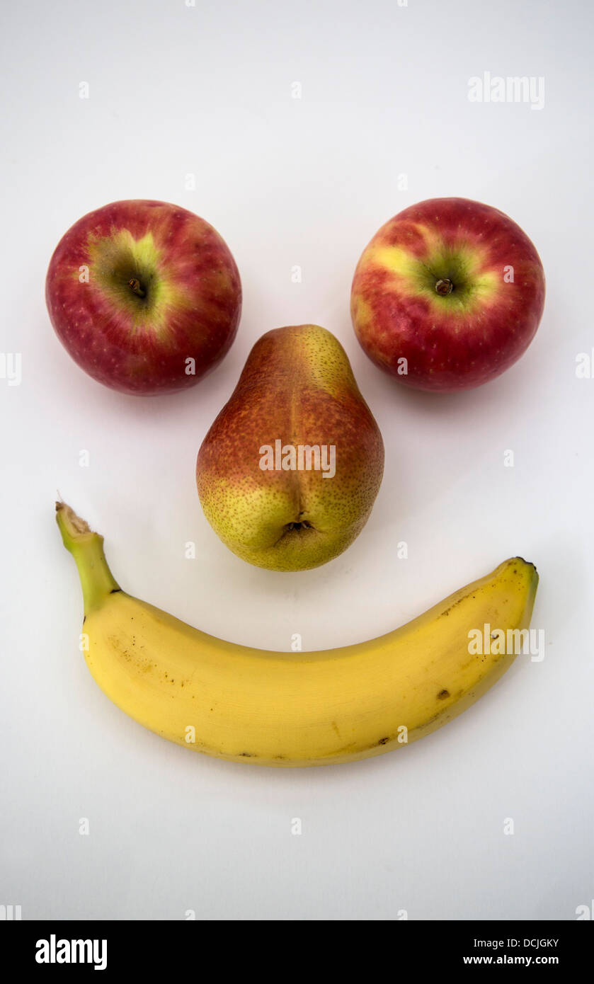 Due mele, una pera e una banana guardando come una faccina sorridente. Foto Stock
