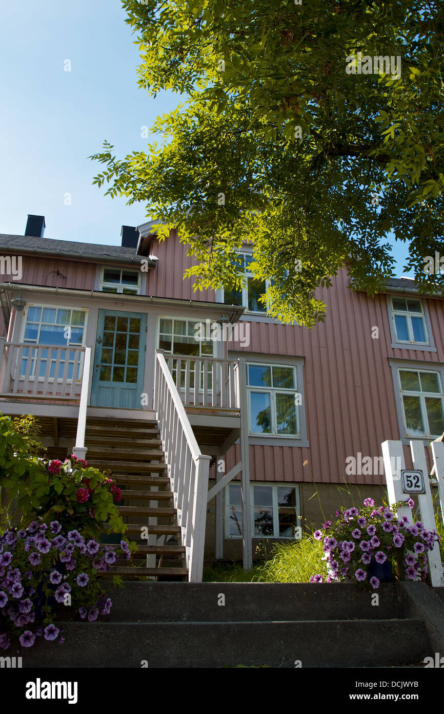 Rosa clapboard casa sotto un albero in estate il sole nelle regioni artiche della Norvegia Foto Stock