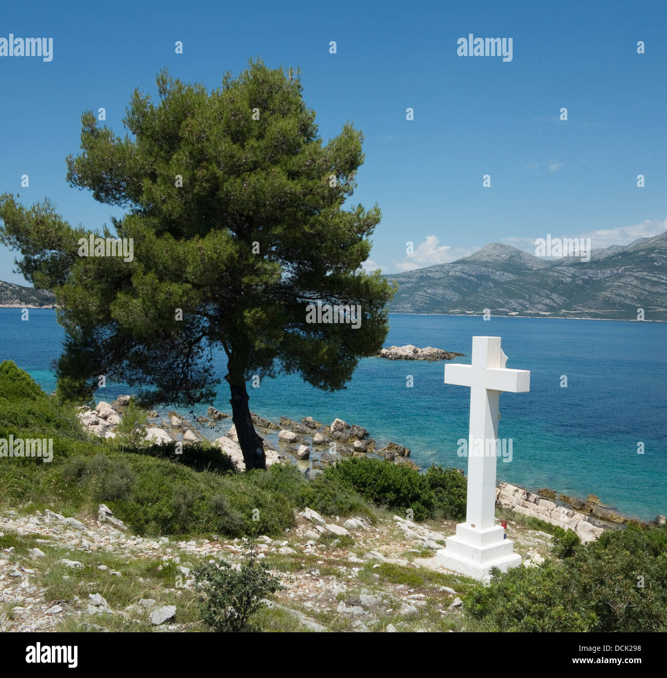 Pietra Bianca Croce dal mare blu sulla giornata di sole da terra sull isola di Lopud con la parte continentale della Croazia a distanza Foto Stock