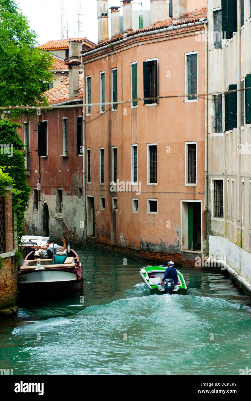 Un piccolo canale di Venezia con un uomo sulla sua barca. Foto Stock