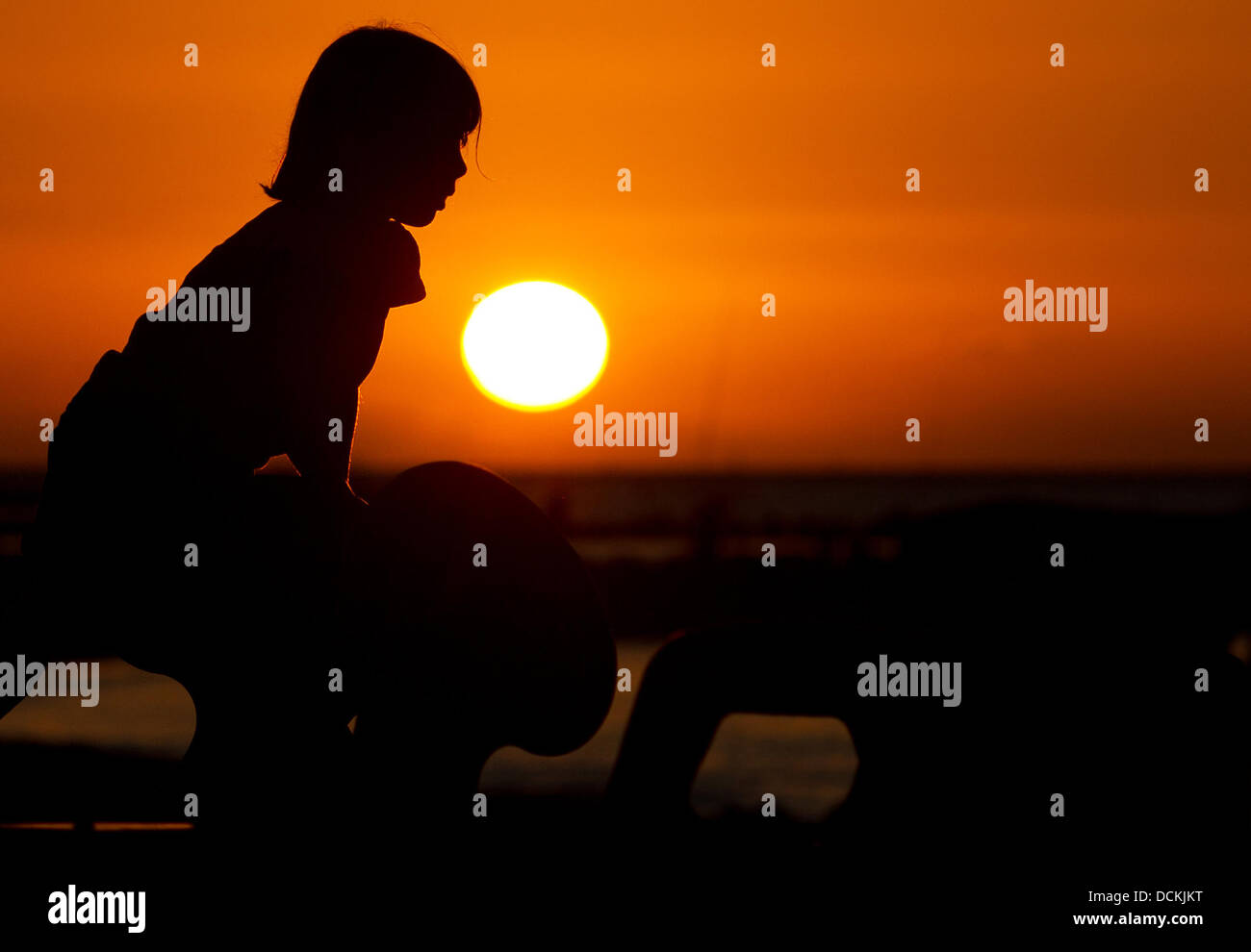 Una bambina gioca su un parco giochi durante il tramonto sulla costa del mare Batlic nei pressi di Schoenberg/Repubblica federale di Germania il 3 agosto 2013. Foto: Fabian Stratenschulte Foto Stock