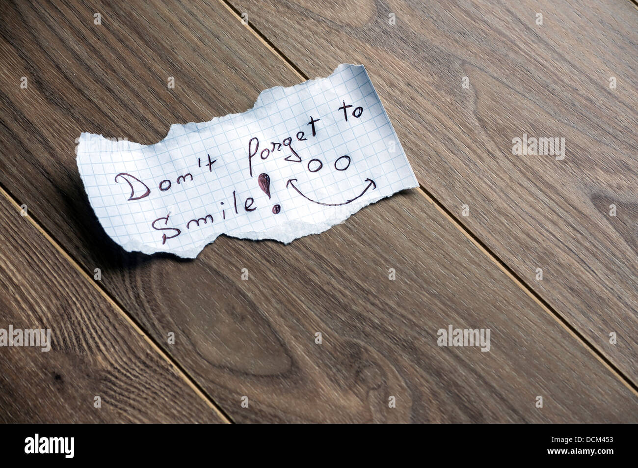 Non dimenticate di sorridere - La scrittura a mano il testo su un pezzo di carta su uno sfondo di legno con spazio per il testo Foto Stock