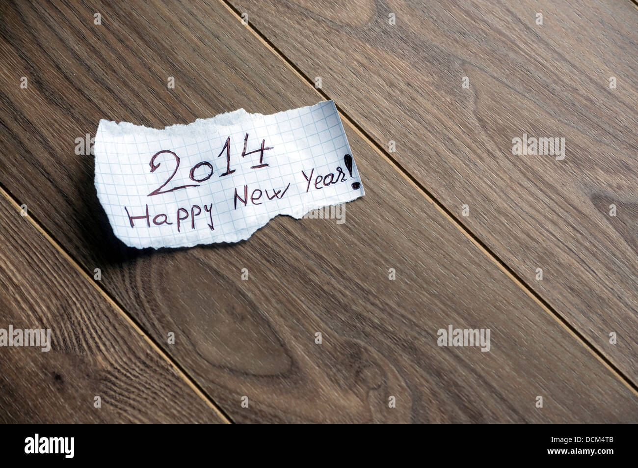 Felice anno nuovo 2014 - La scrittura a mano il testo su un pezzo di carta su uno sfondo di legno con spazio per il testo Foto Stock