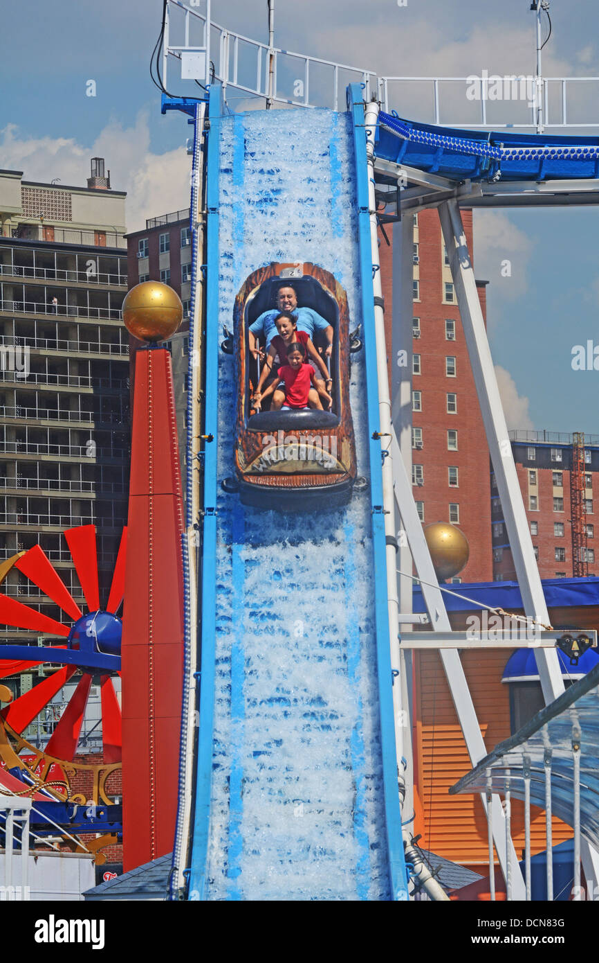 Con appartamento case in background una famiglia scorre il fiume selvaggio attrazione al luna park di Coney Island Brooklyn, New York Foto Stock
