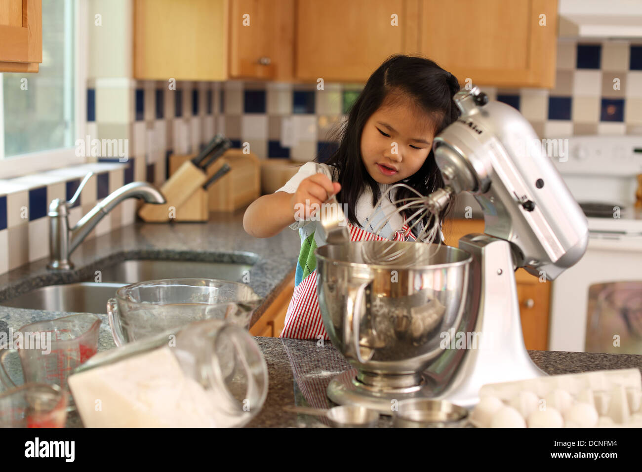 Ragazza giovane aiutando la madre cuocere in cucina Foto Stock