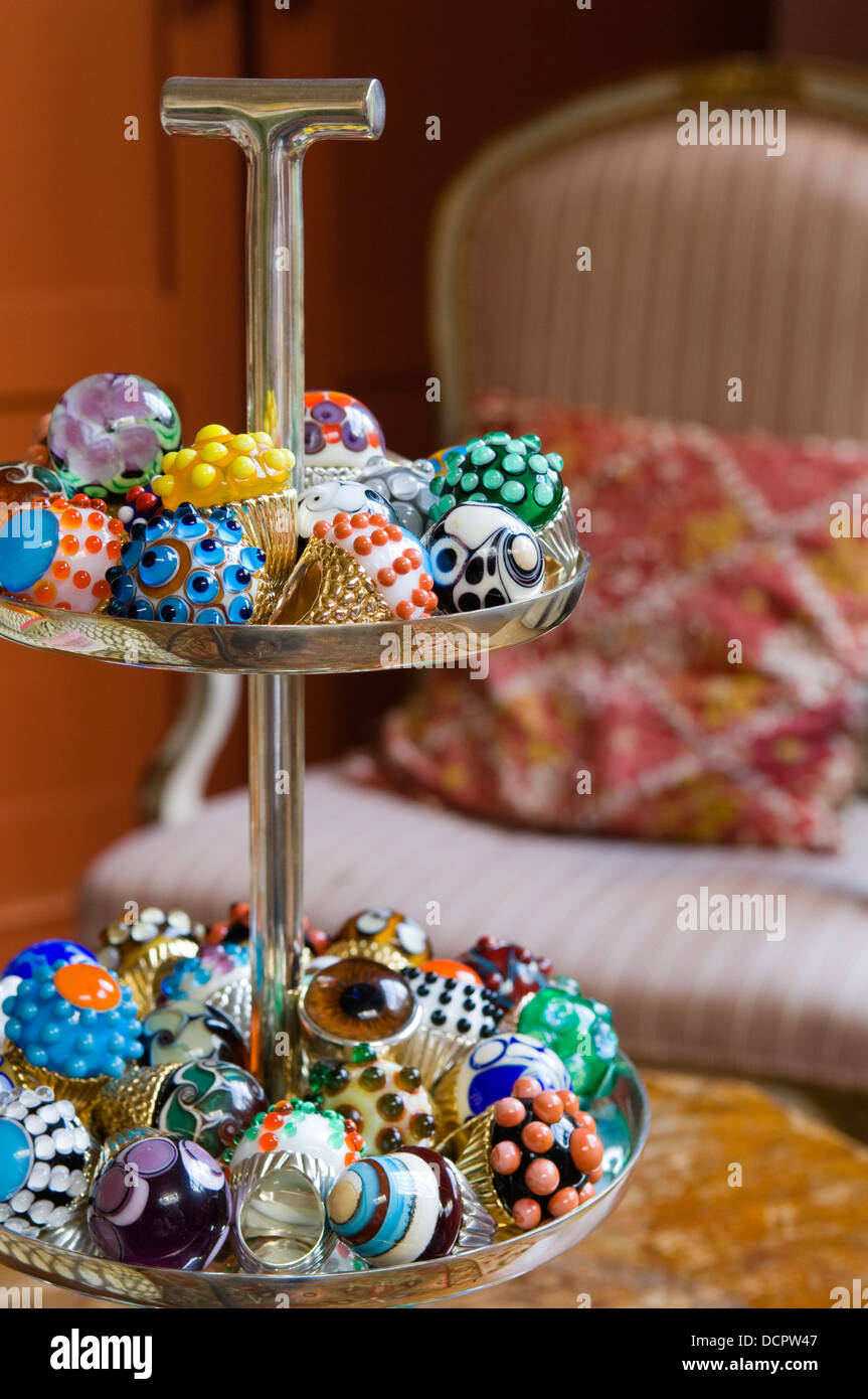 Un assortimento di chunky anelli in vetro realizzato gioiellerie Legge & cervello in stand a più livelli Foto Stock