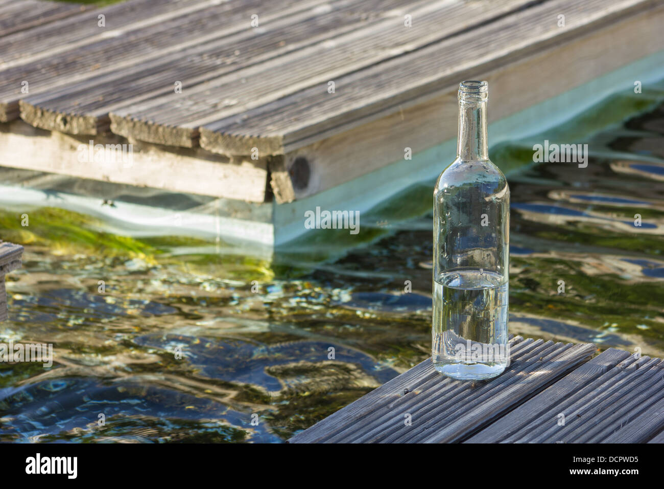 Bottiglia trasparente con acqua vicino a un lago Foto Stock