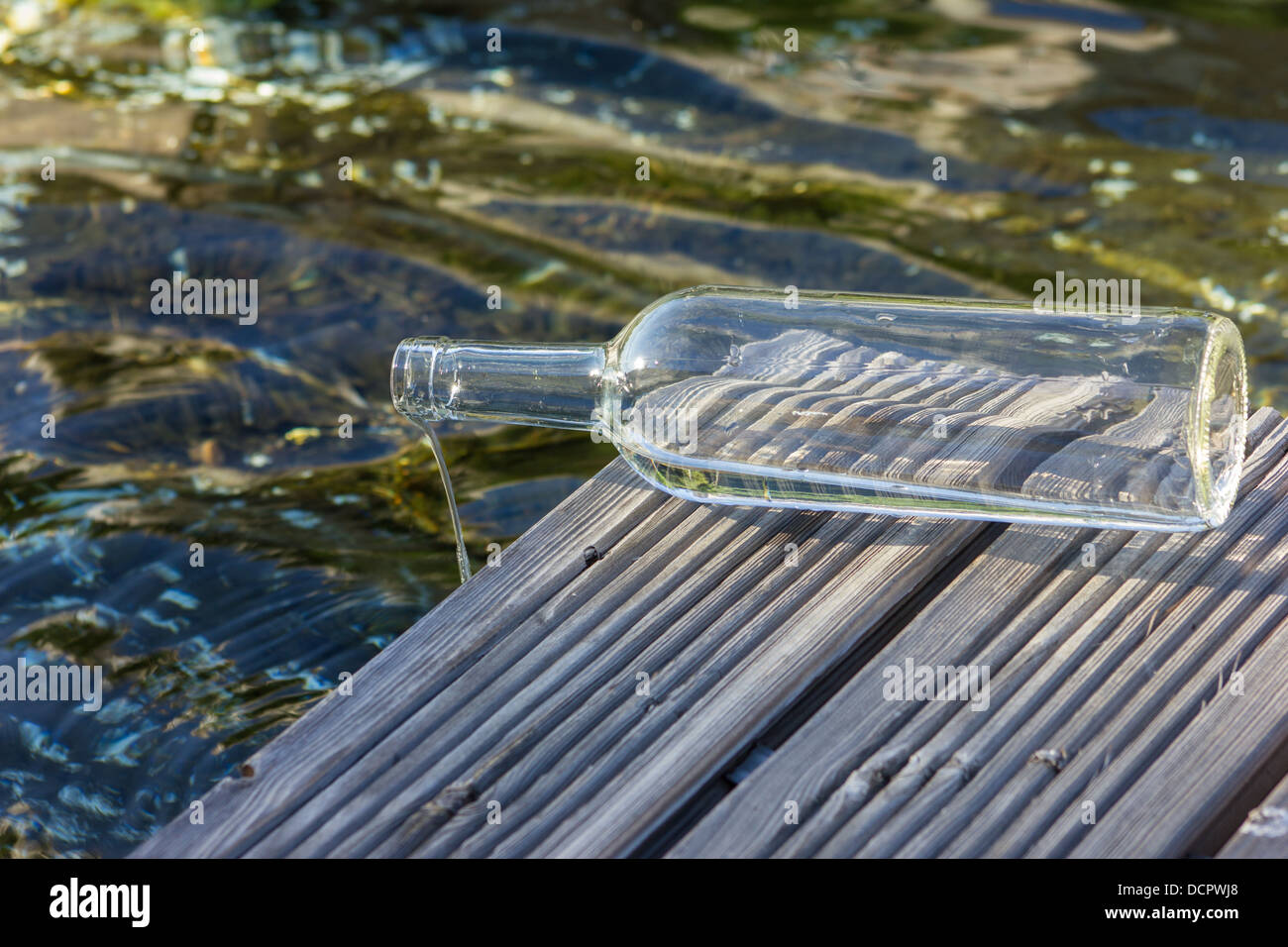 Bottiglia trasparente con acqua vicino a un lago Foto Stock