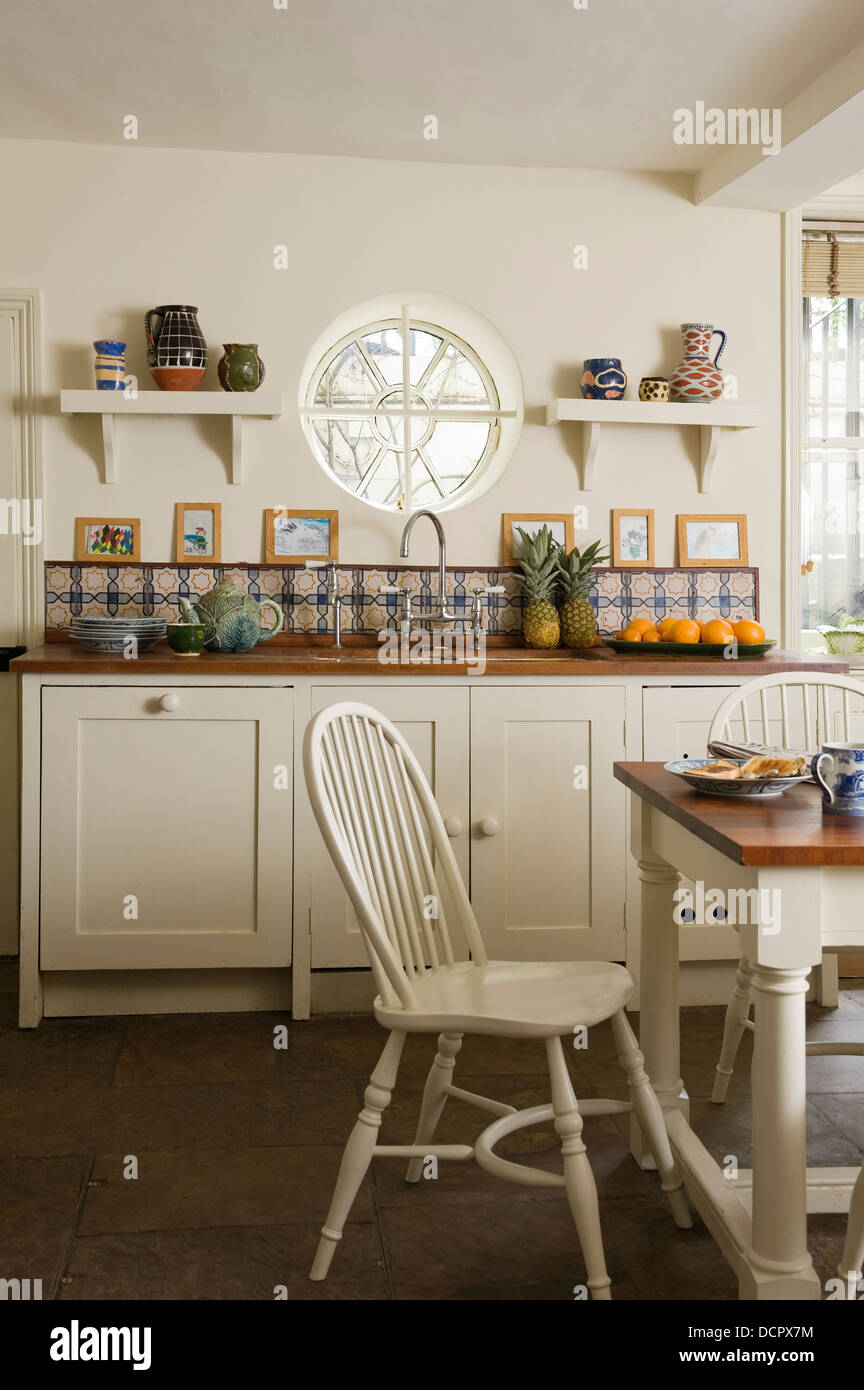 Colorate piastrelle napoletana in cucina bianca con oblò e Windsor spranga sedie indietro Foto Stock