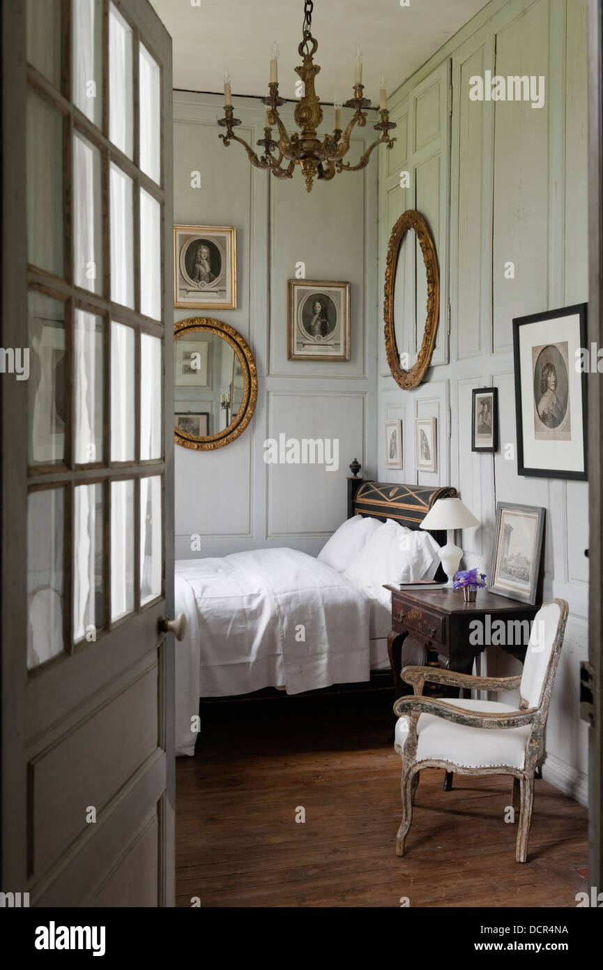 Visualizzare attraverso la porta aperta per l'incantevole camera da letto con pareti in legno pannelli e pezzi di antiquariato francese Foto Stock