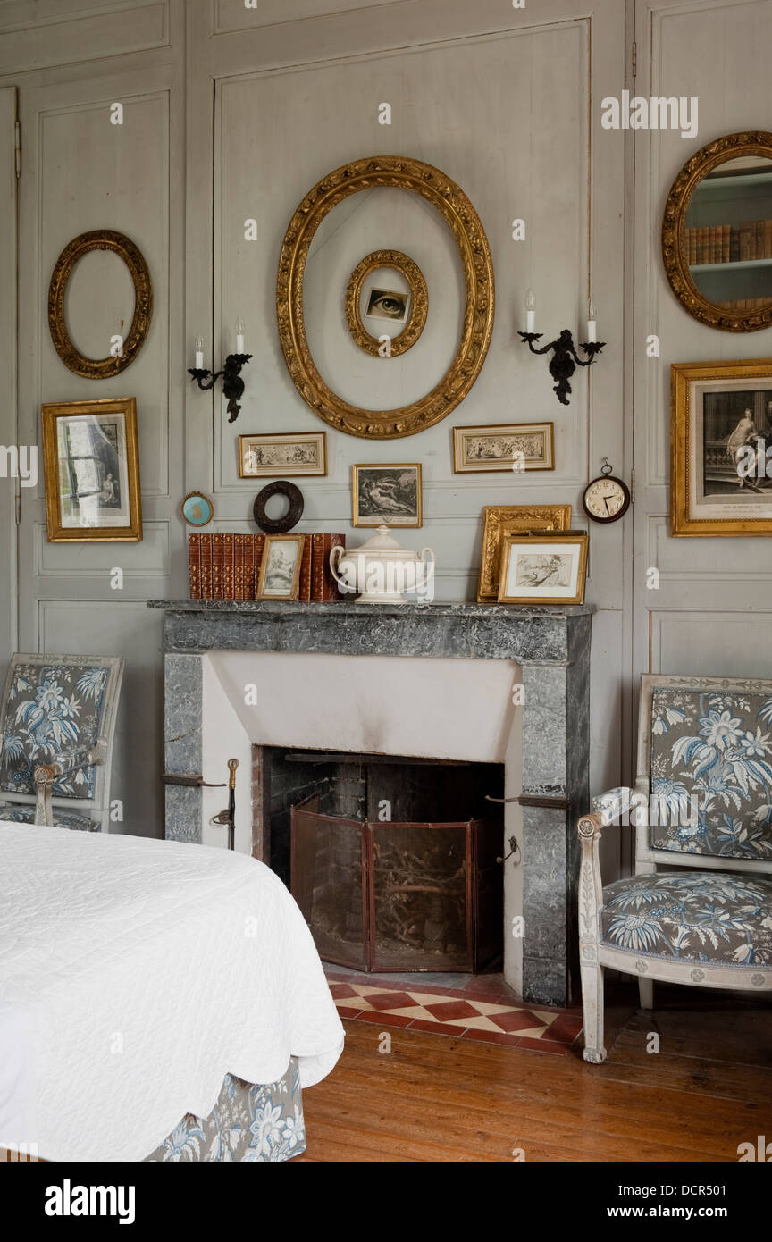 Caminetto in marmo affiancato da sedie francesi imbottiti in tessuto Movic in camera da letto con legno pannelli a parete Foto Stock
