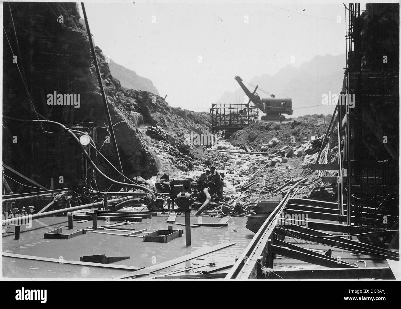 Durante un'alluvione, l'acqua attraversa la terra e la diga di riempimento della roccia sul portale di uscita del tunnel di deviazione n. 2. L'evento mette in evidenza l'impatto delle catastrofi naturali sulle strutture ingegneristiche e la loro capacità di gestire improvvisi picchi d'acqua. Foto Stock