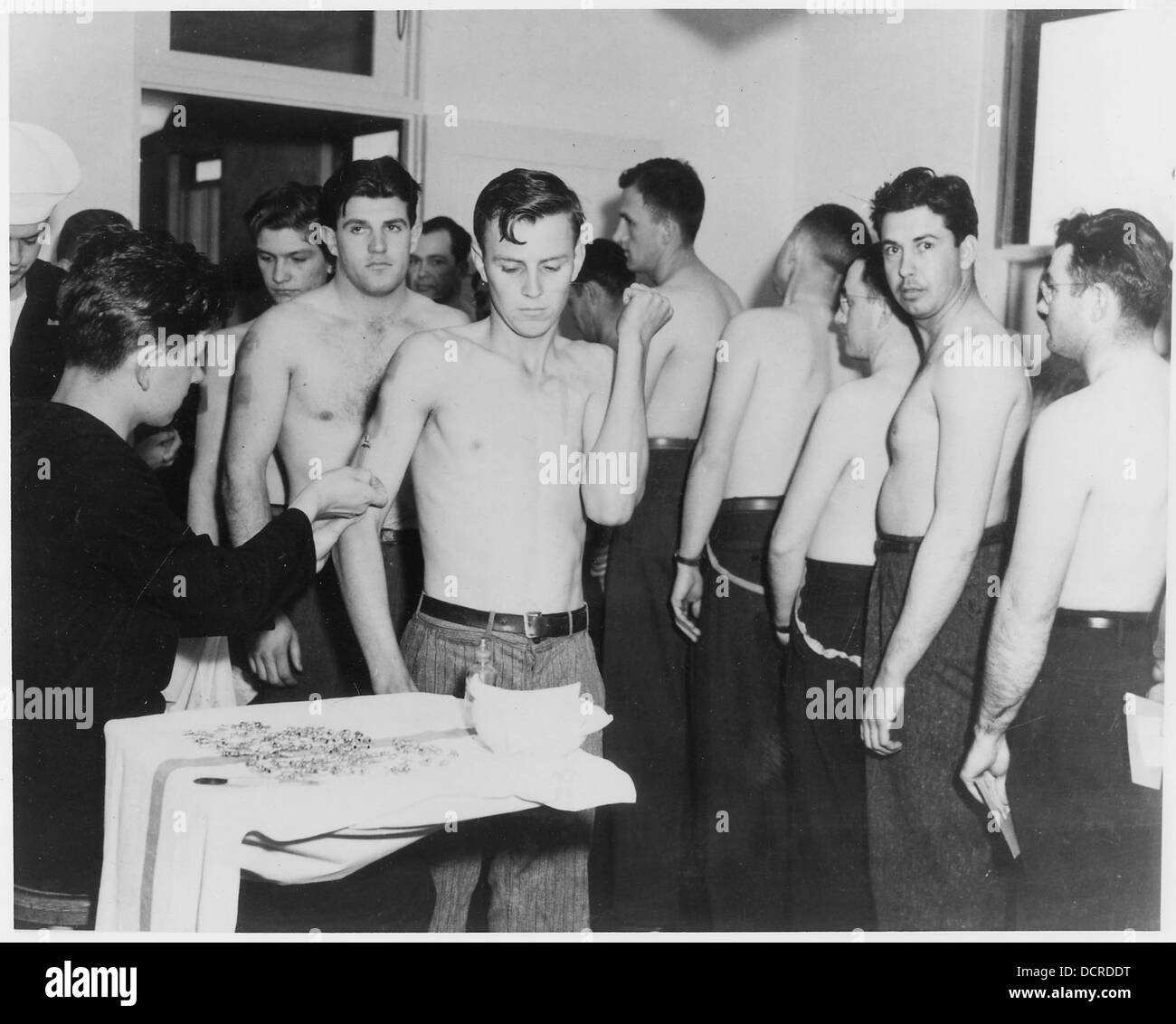 Le reclute ricevono inoculazioni presso il dispensario della U.S. Naval Training Station di San Diego, California, parte del loro processo di induzione militare. Foto Stock