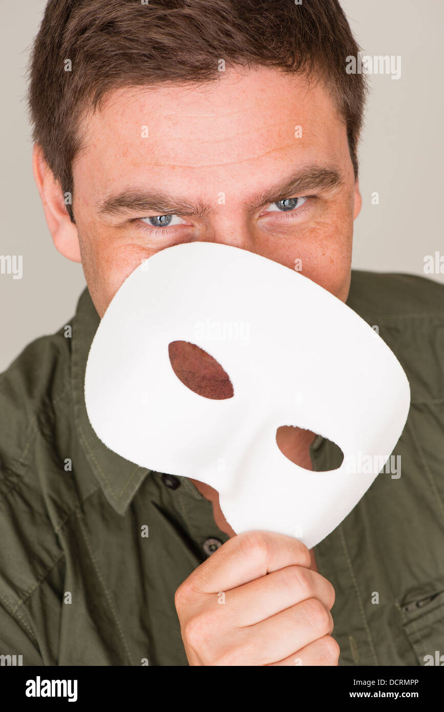 Felice e uomo sorridente di nascondersi dietro la maschera bianca Foto Stock