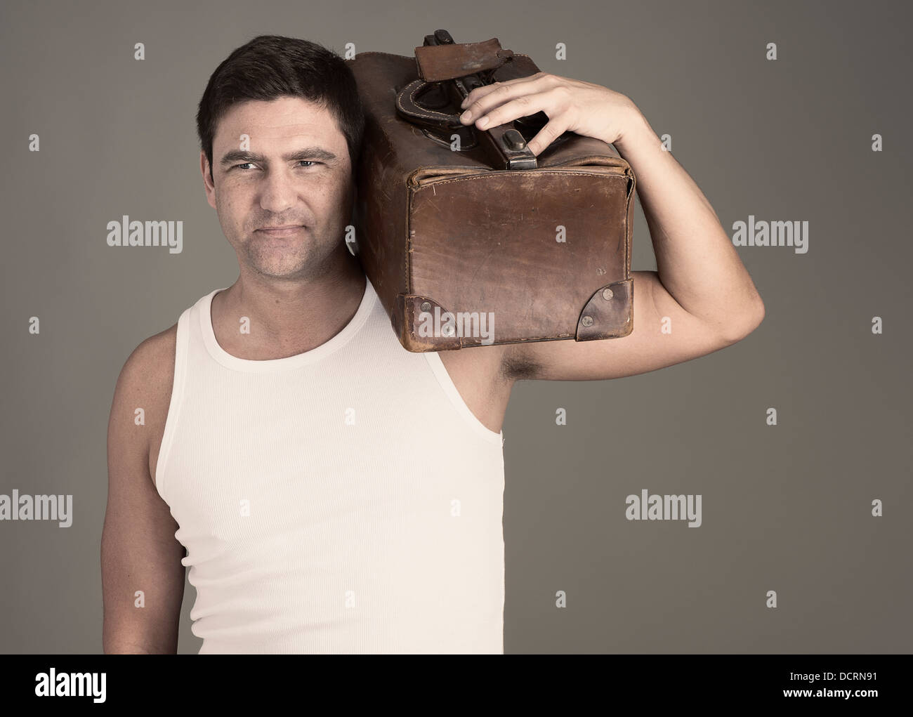Determinato uomo in bianco il serbatoio di contenimento superiore in pelle marrone borsa bagagli sulla sua spalla Foto Stock
