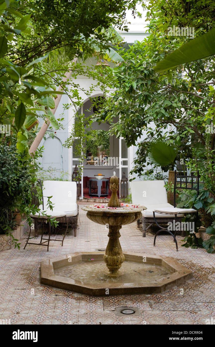 Marocchino in piastrelle cortile con fontana e sedie a sdraio Foto Stock