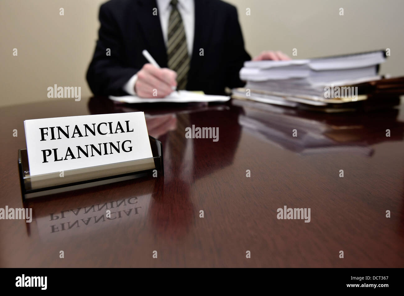 Uomo seduto alla scrivania tenendo pen carte con business card per la pianificazione finanziaria Foto Stock