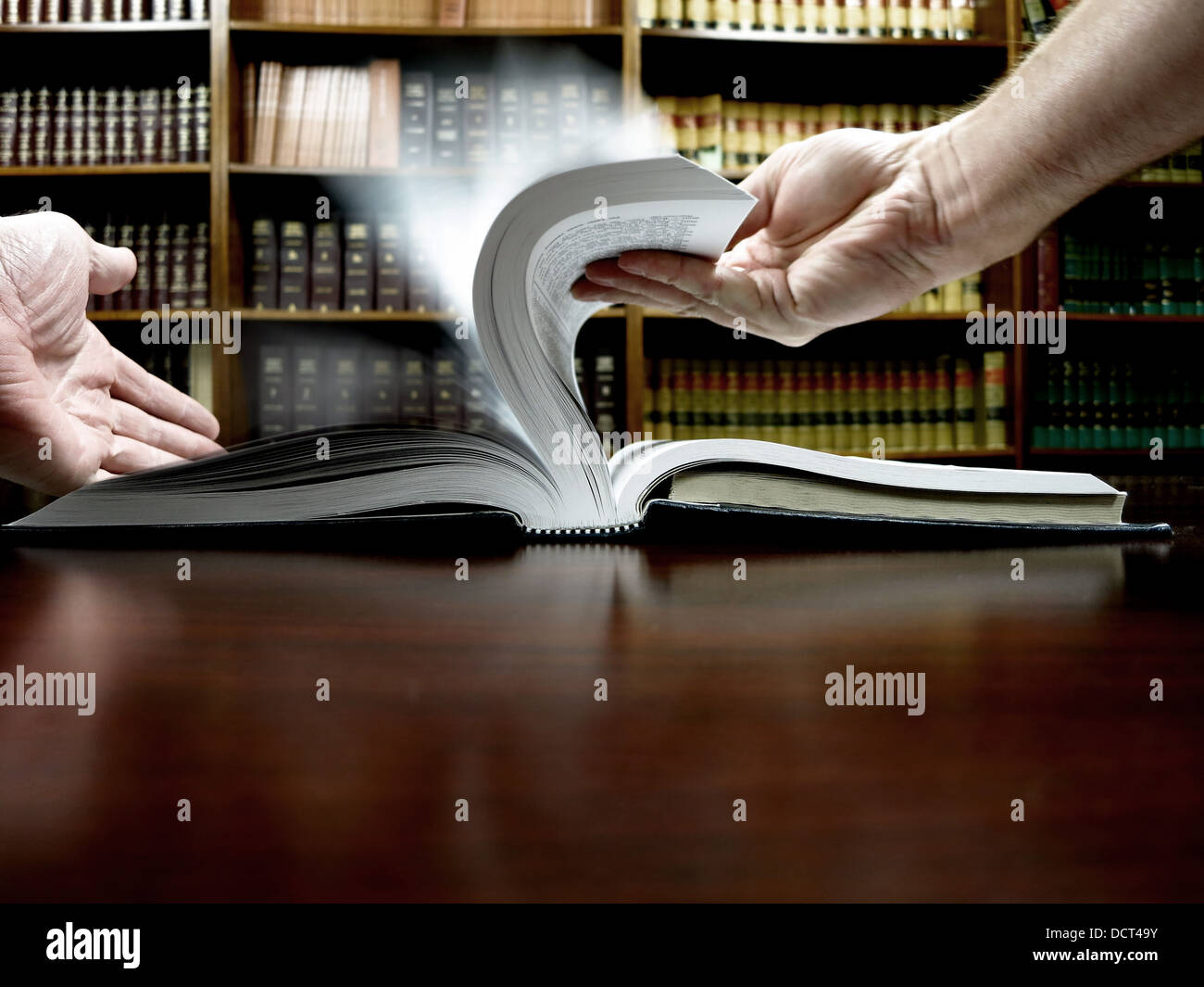 Le mani sono in possesso di un vecchio libro con Libreria in background Foto Stock