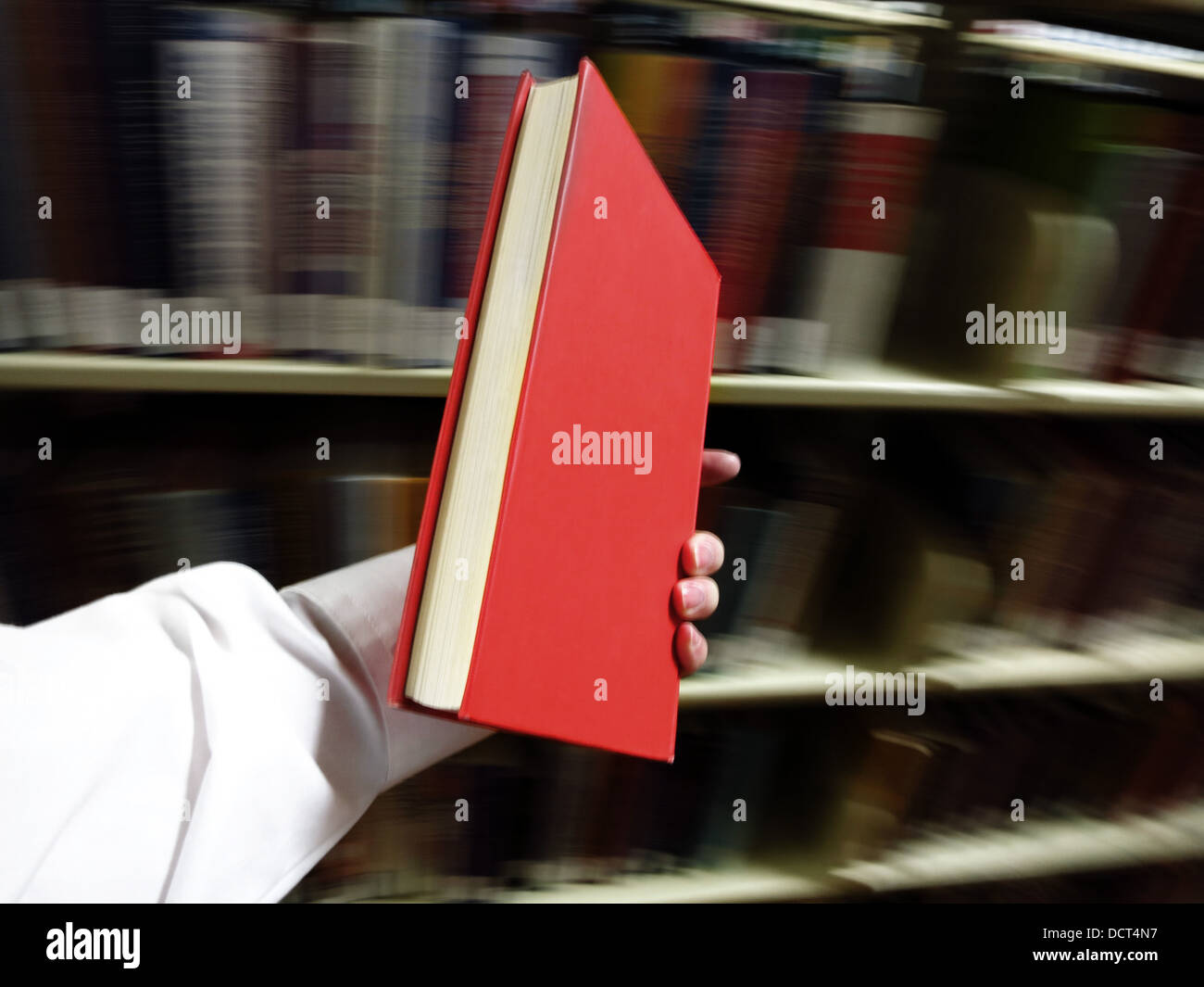 Mani un libro rosso con Libreria in background Foto Stock