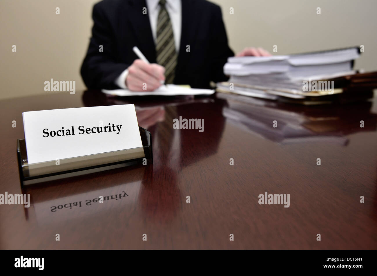 Uomo seduto alla scrivania tenendo pen carte con business card per la sicurezza sociale Foto Stock