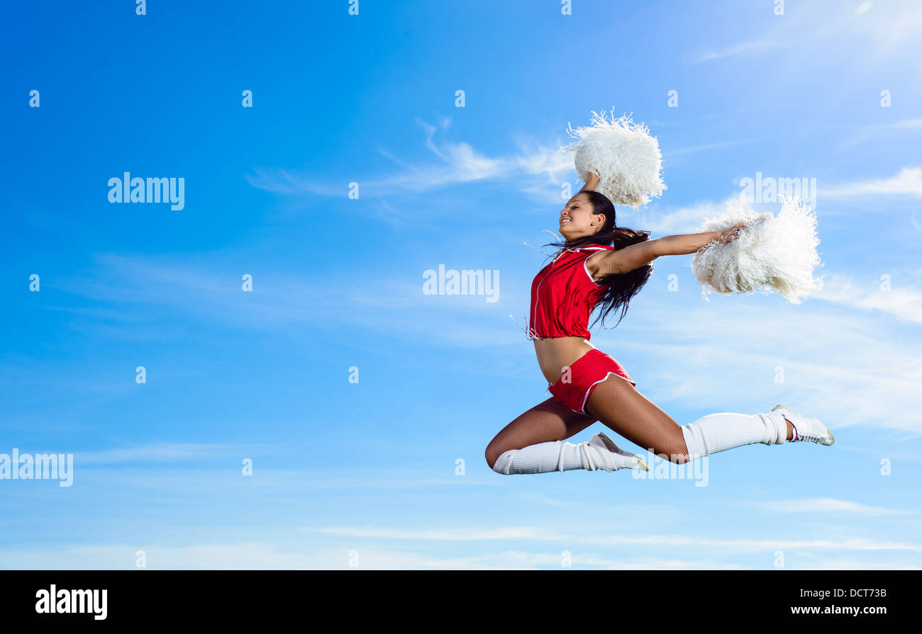 Giovani cheerleader in costume rosso jumping Foto Stock