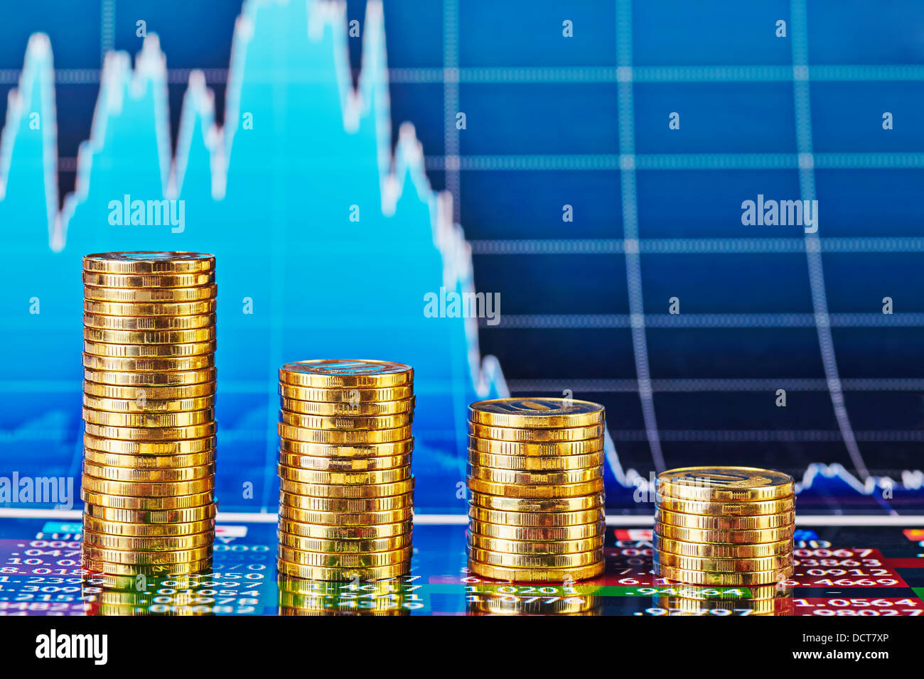 Tendenza ribassista grafico finanziario e quattro pile di monete d'oro. Messa a fuoco selettiva Foto Stock