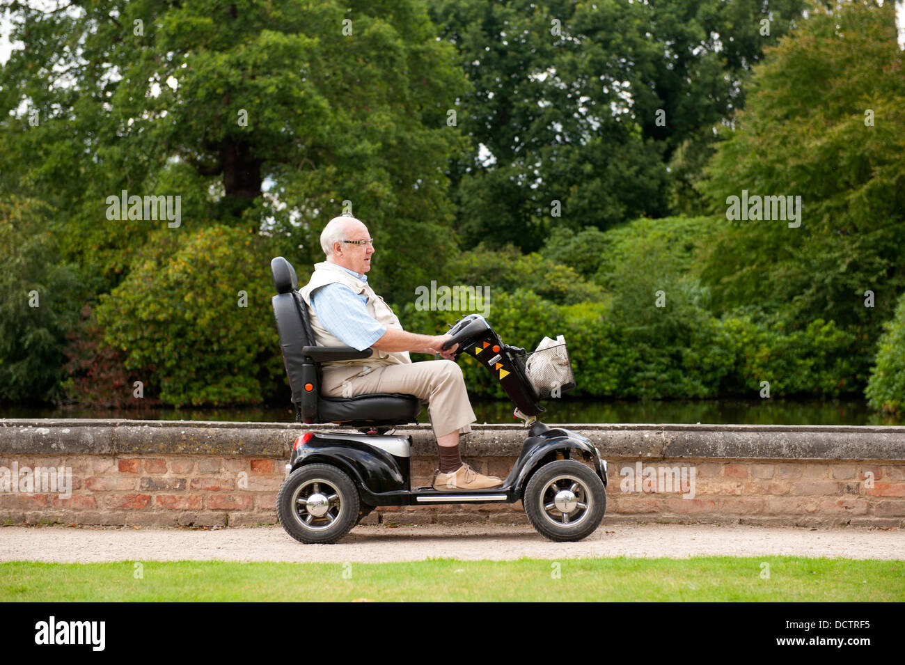 Senior uomo a cavallo di un scooter di mobilità Foto Stock