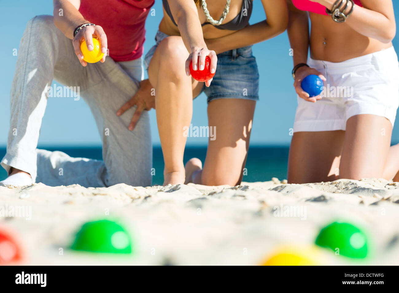 Un gruppo di giovani giocando boule sulla spiaggia in sabbia all'aperto in estate Foto Stock