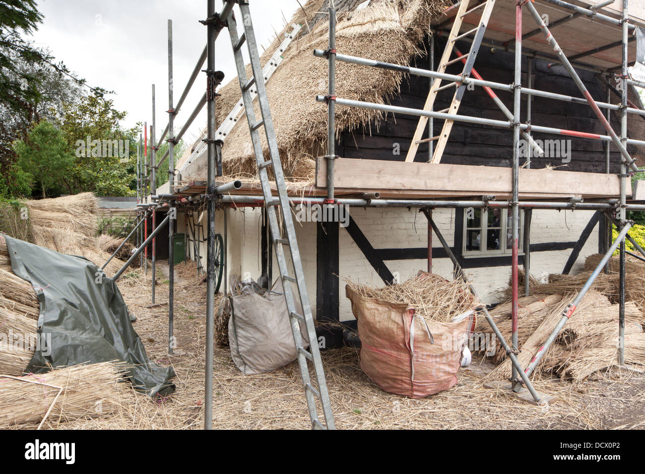 Le riparazioni del tetto di un cottage con il tetto di paglia, Gloucestershire, England, Regno Unito Foto Stock