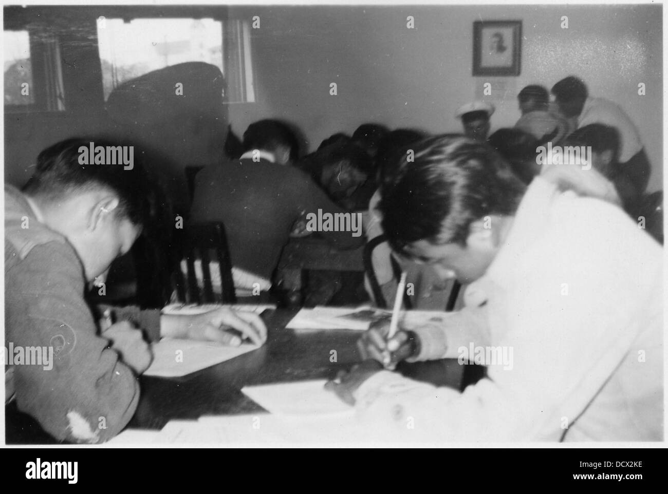 Questa immagine cattura le persone che compilano i moduli di arruolamento per la Marina degli Stati Uniti. La fotografia evidenzia il processo di adesione ai militari durante un periodo significativo della storia. Foto Stock