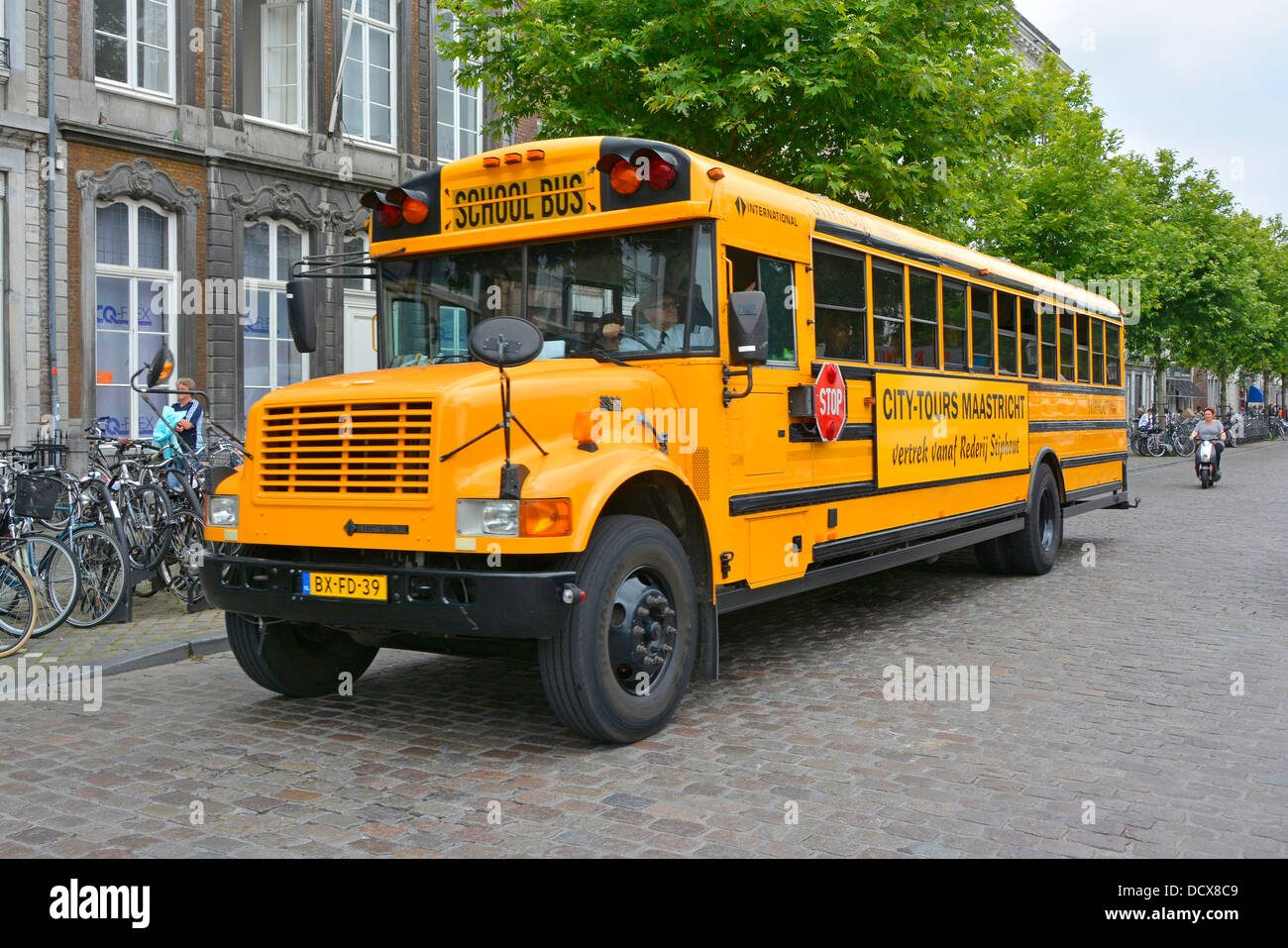 Maastricht City Street scene vista frontale laterale scuolabus giallo americano adattato per le visite turistiche del centro città Limburgo Paesi Bassi Europa Foto Stock