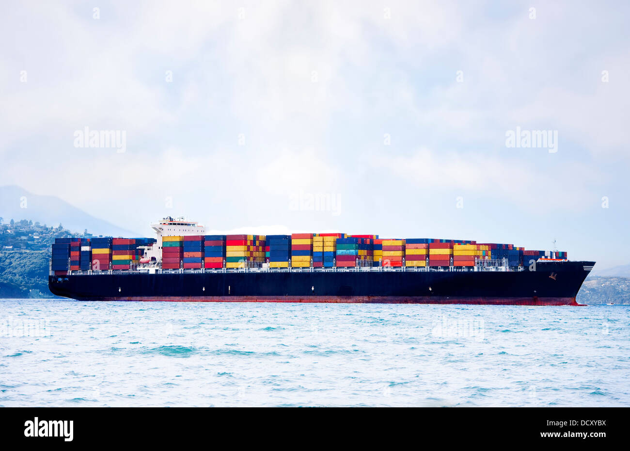 Grande nave da carico in acqua colorata che trasportano contenitori di spedizione Foto Stock