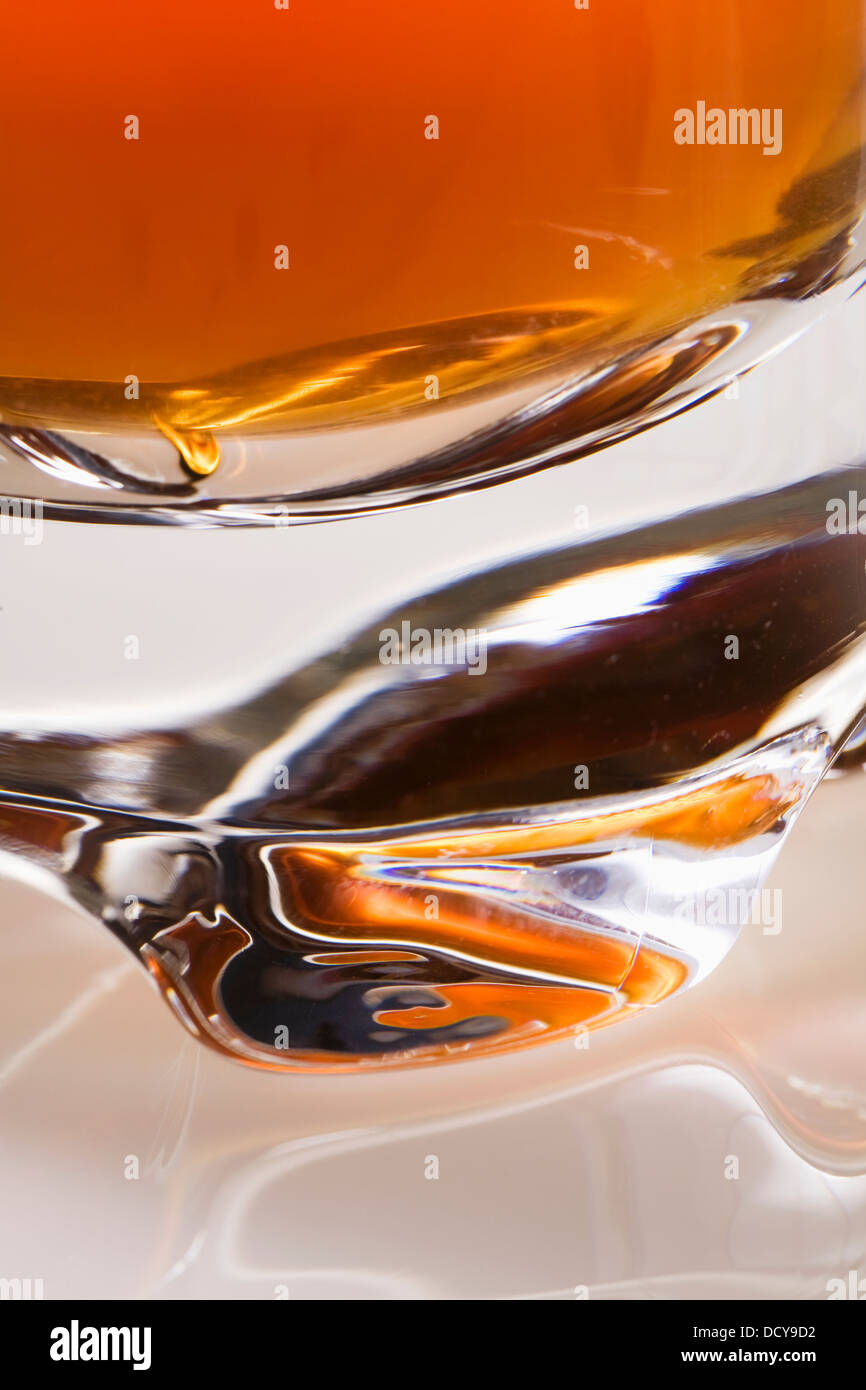 In primo piano della base del bicchiere riempito con un liquido arancione Foto Stock