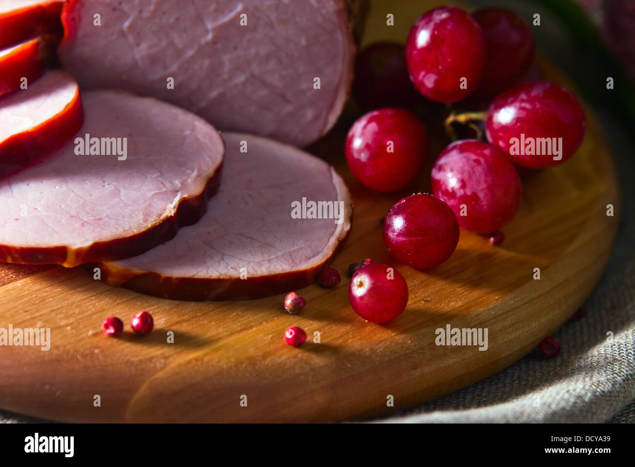 Carne affumicata e uva rossa su una tavola di legno Foto Stock