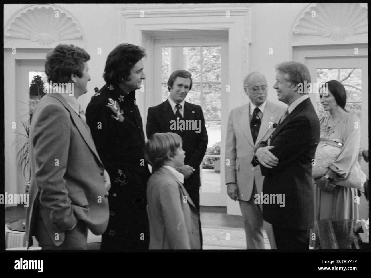 Questa fotografia mostra l'ex presidente degli Stati Uniti Jimmy Carter con la leggenda della musica country Johnny Cash e la sua famiglia. La foto evidenzia un momento di connessione tra le due figure di spicco della politica e dell'intrattenimento americano. Foto Stock