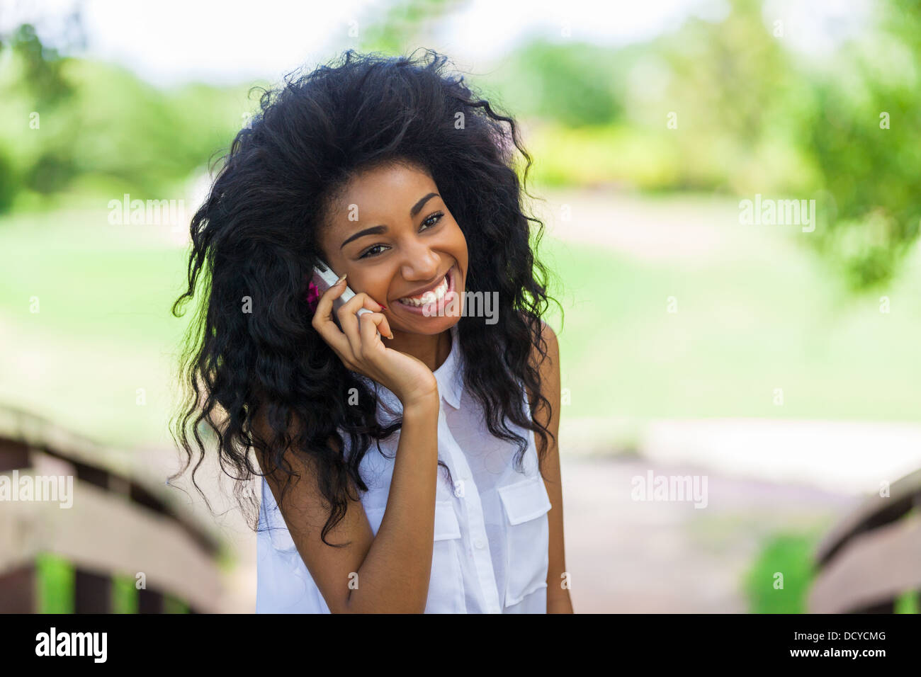 Adolescente sorridente ragazza nera utilizzando un telefono cellulare - popolo africano Foto Stock