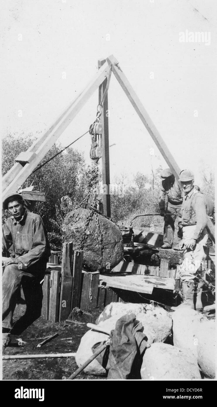 Questa immagine mostra una grossa roccia sollevata da un paranco, probabilmente per scopi di scavo o di costruzione. L'operazione è in corso alla primavera 5E3, mettendo in evidenza le attrezzature industriali e le tecniche di movimentazione rocce. Foto Stock