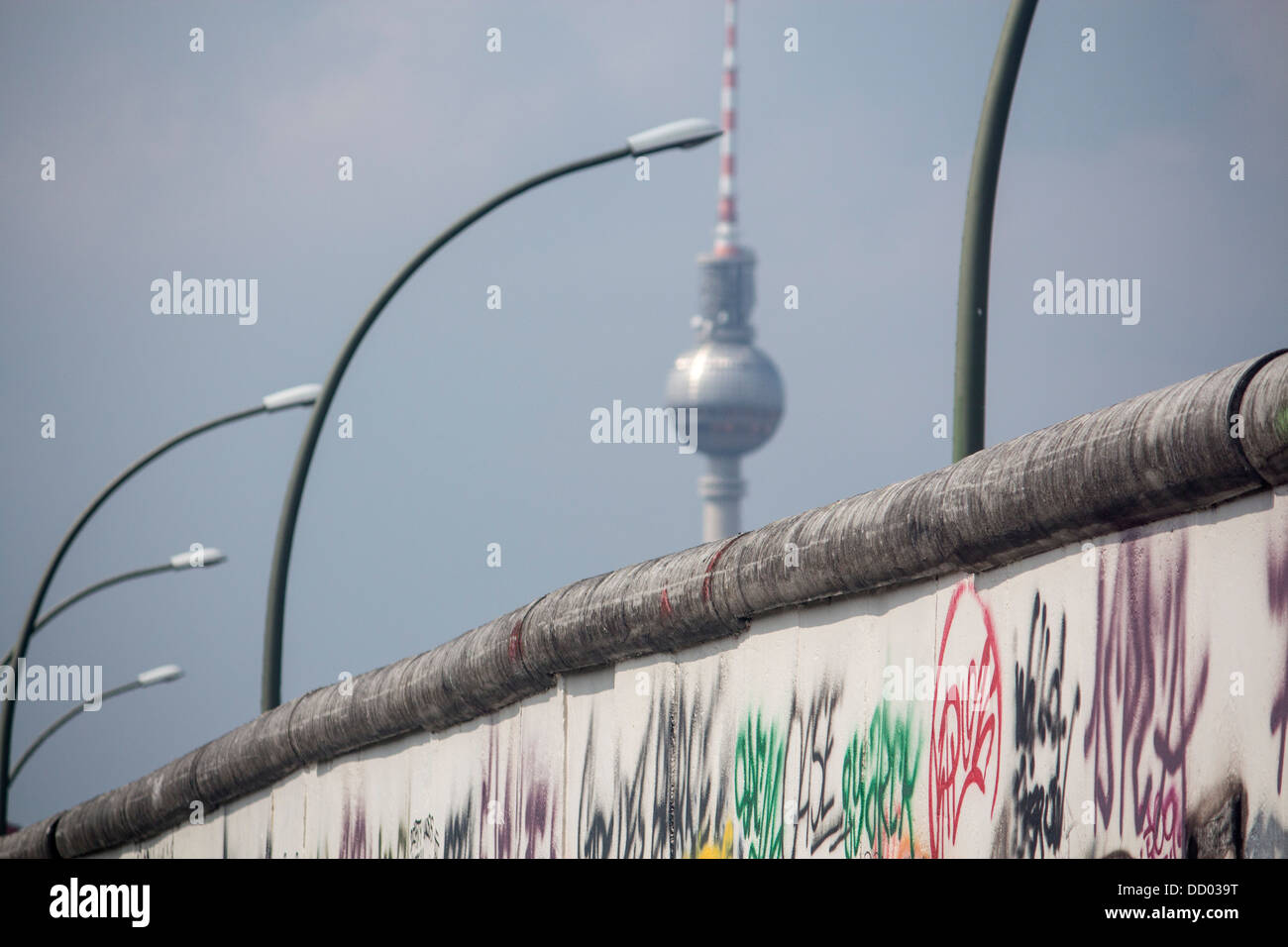 La sezione del muro di Berlino con graffiti e Fernsehturm Torre della TV di distanza Berlino Germania Foto Stock