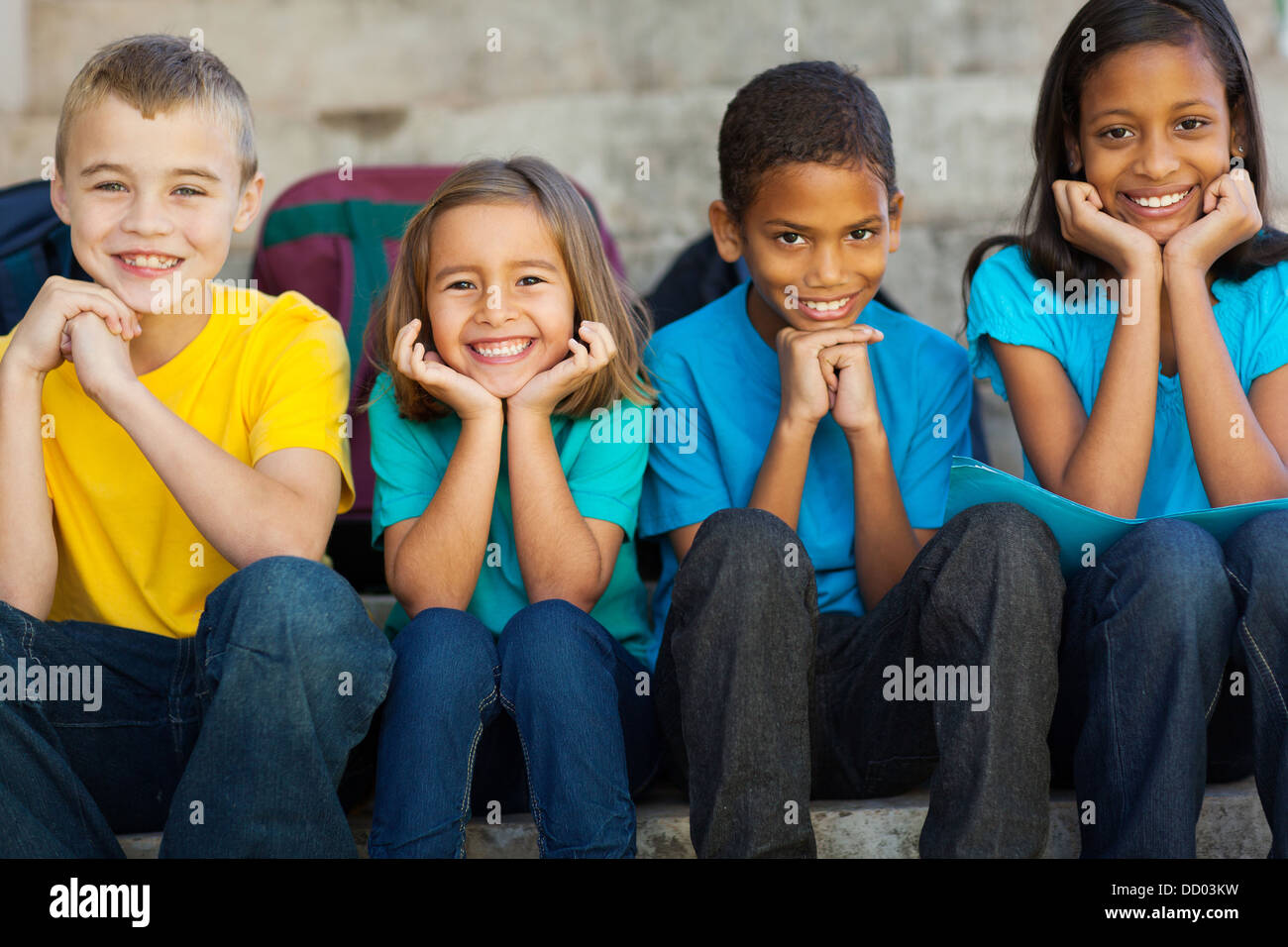 Allegro scuola primaria i bambini seduti all'aperto Foto Stock