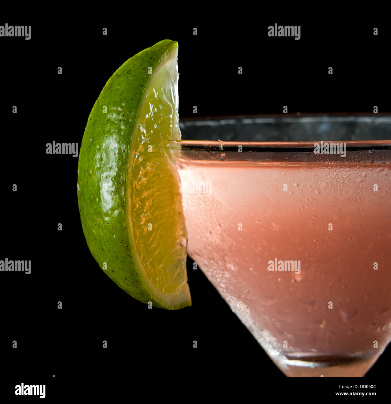 Uno spicchio di lime sul bordo di una coppetta Martini utilizzato come guarnire isolata su uno sfondo nero Foto Stock